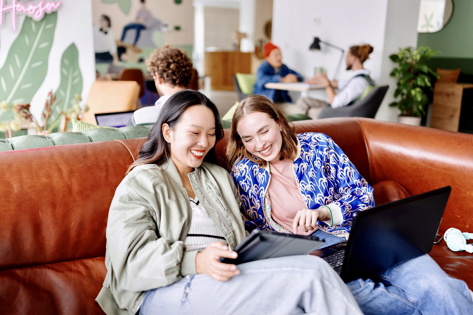 Deux jeunes femmes utilisant une tablette et un ordinateur pour planifier des vacances en camping.