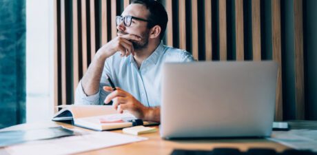 Professionnel réfléchissant à son bureau devant un ordinateur portable, illustrant la prise de décision stratégique dans un groupe multi-sites.