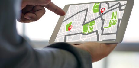 Personne utilisant une tablette affichant une carte interactive avec des points de localisation, illustrant la réservation d’emplacement en ligne sur plan pour un camping.